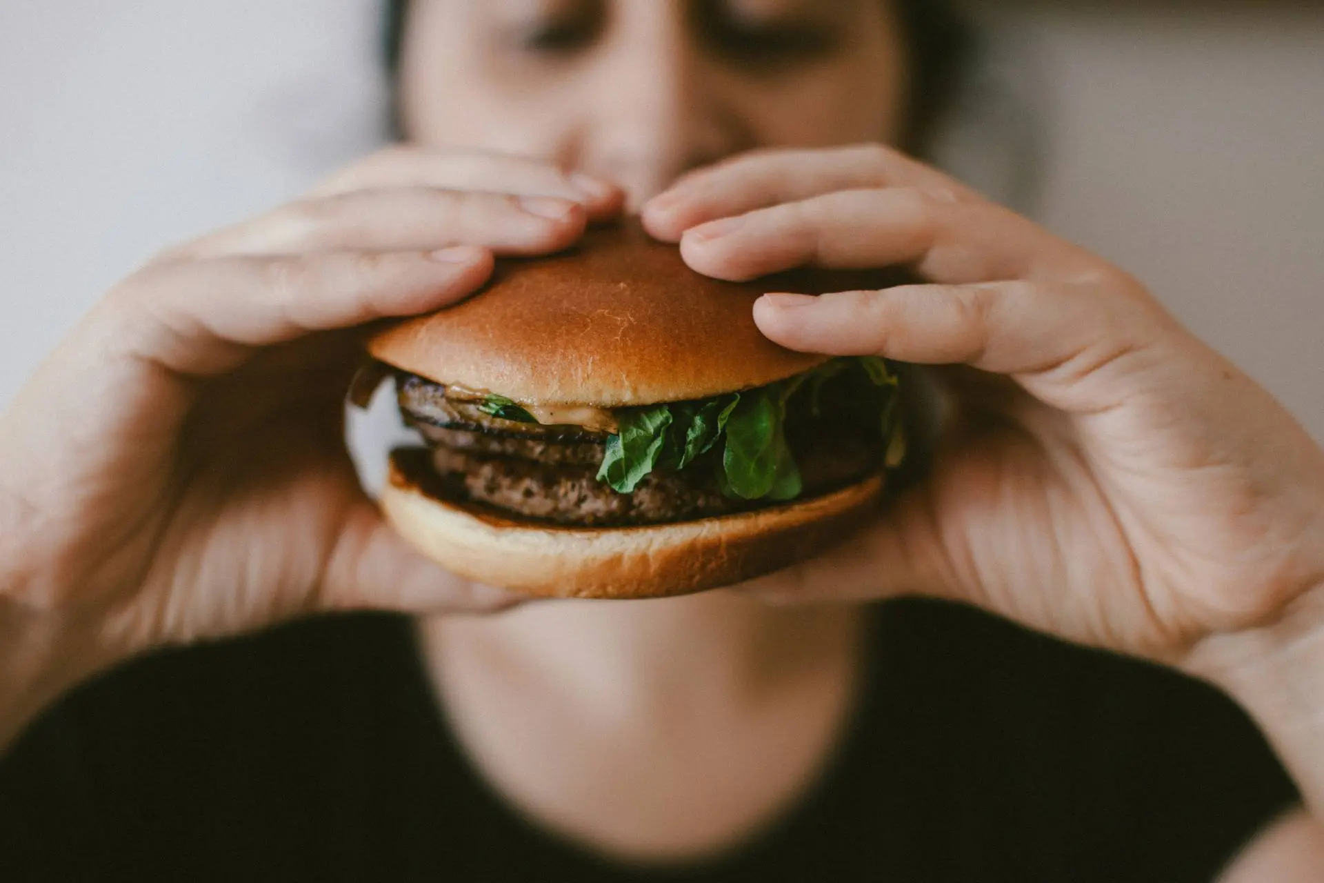 Person holding burger showing gut-brain axis appetite control signals from new study on eating behavior.