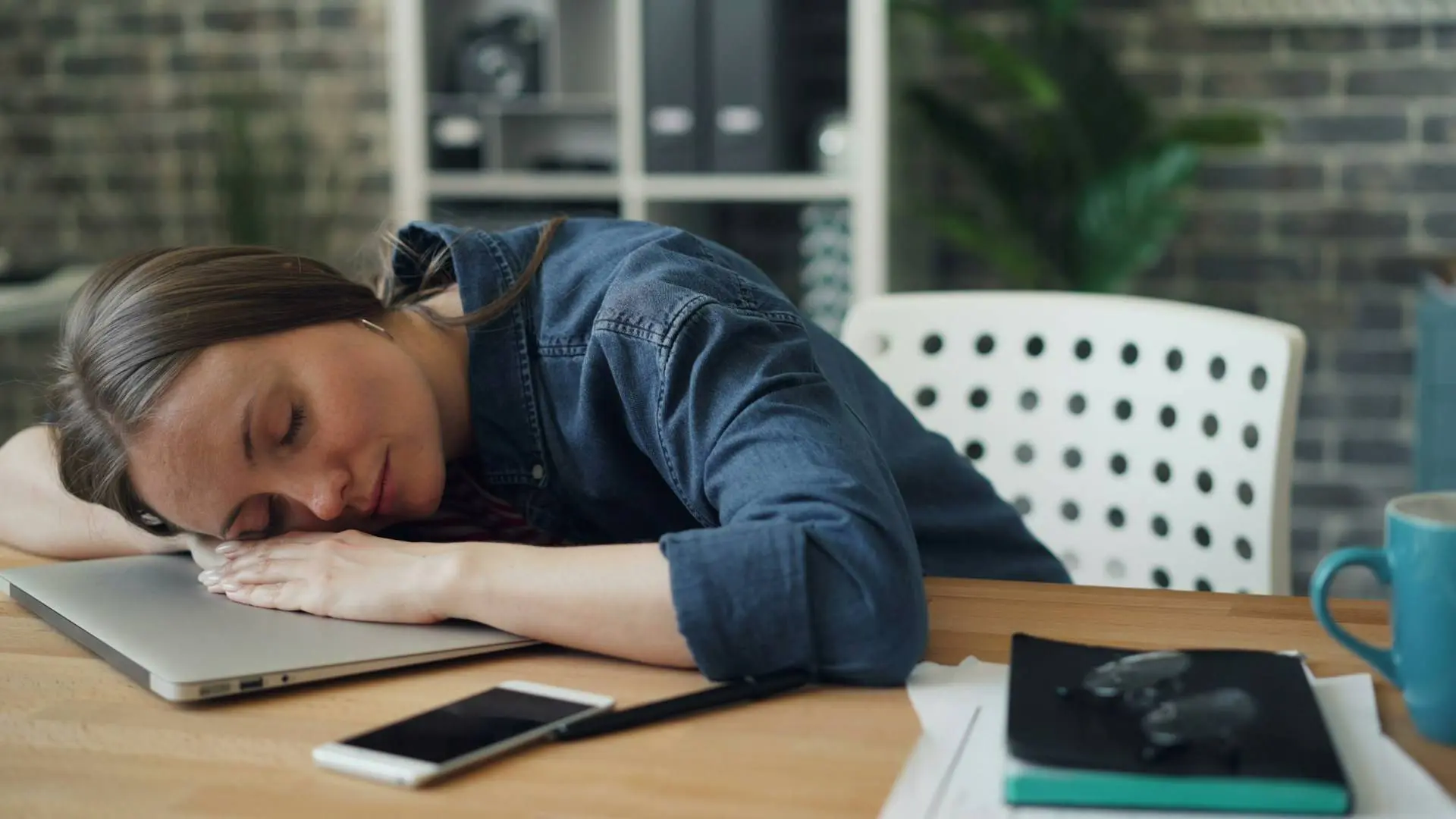 Exhausted woman with head down on laptop demonstrating why energy management beats time management for sustainable productivity.