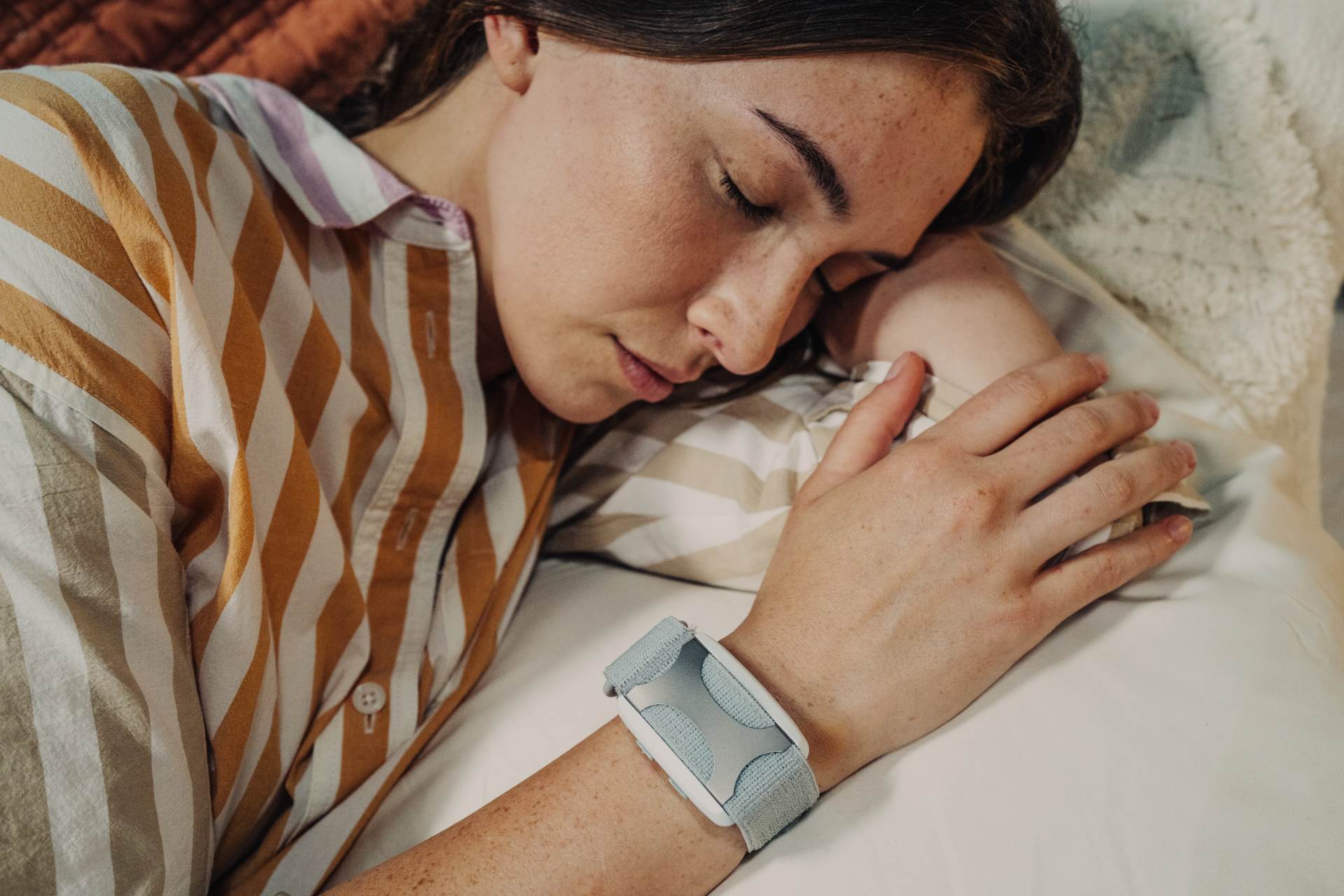 Woman sleeping peacefully wearing Apollo Neuro device